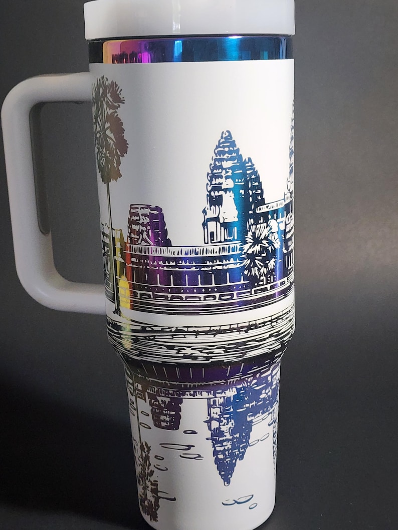 May include: White travel mug with a black and white image of Angkor Wat, a temple complex in Cambodia. The mug has a rainbow iridescent finish around the top.