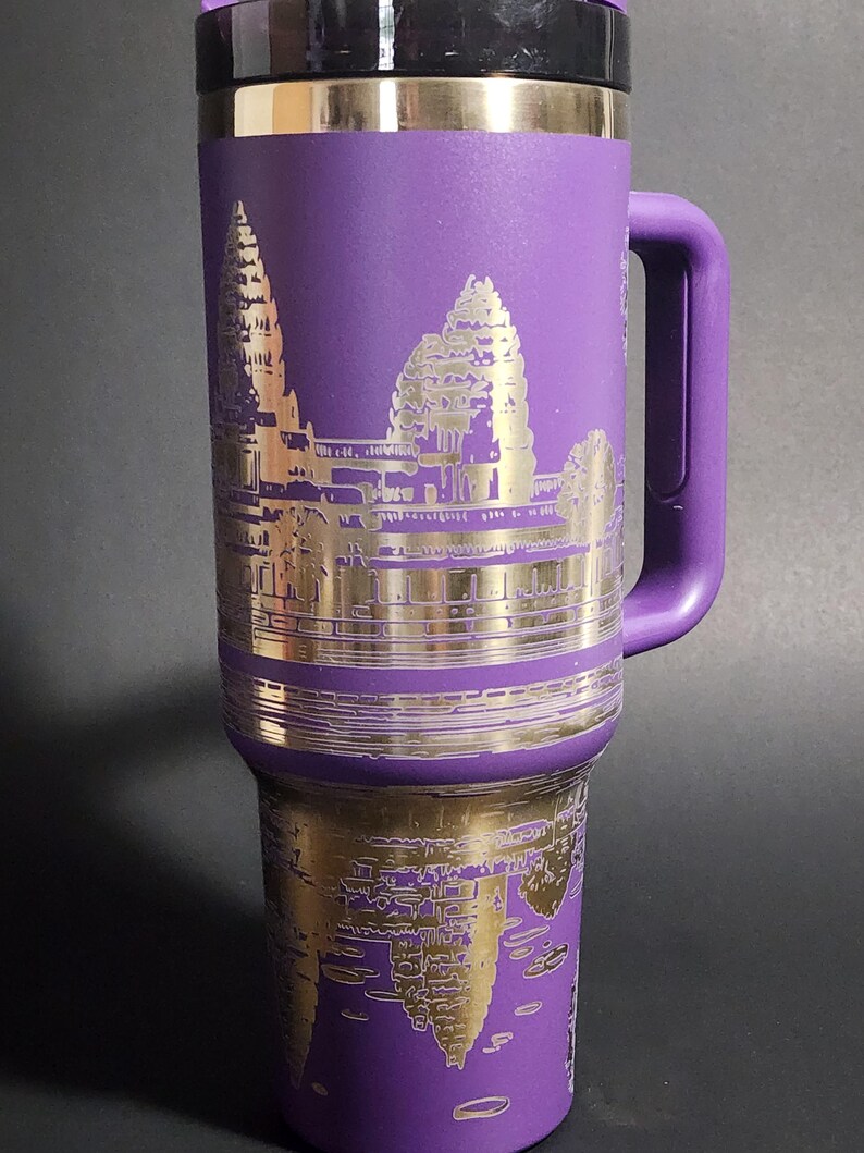 May include: Purple stainless steel travel mug with a gold-colored image of Angkor Wat temple on the front.