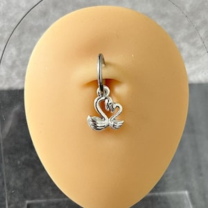 May include: Silver belly button ring with a dangling charm of two swans facing each other.