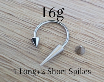 May include: A silver 16g circular barbell with a long spike on one end and two short spikes on the other end. The text "1 Long + 2 Short Spikes" is written below the barbell.