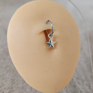May include: A silver star charm dangling from a silver hoop piercing