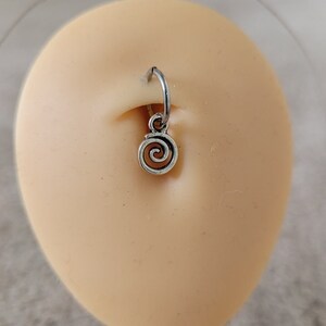 May include: Silver body piercing with a spiral charm. The piercing is in a person's ear.