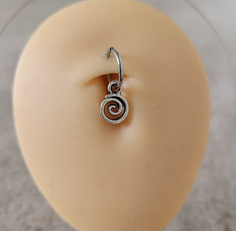 May include: Silver body piercing with a spiral charm. The piercing is in a person's ear.