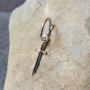 May include: Silver sword charm with a hoop for attaching to a necklace or bracelet.