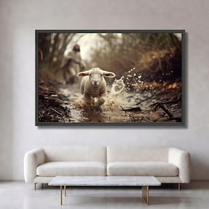 Könnte beinhalten: Ein gerahmter Wandkunstdruck, der ein kleines, cremefarbenes Lamm zeigt, das durch einen flachen, schlammigen Bach läuft. Wasser spritzt um die Hufe des Lammes, während es sich vorwärts bewegt. Im unscharfen Hintergrund steht eine Gestalt zwischen Bäumen.