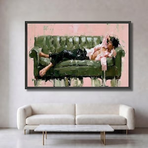 May include: An oil painting depicting a person with dark hair lying on a tufted olive green sofa. The person wears a light pink button-down shirt and black trousers. The background is a solid light pink colour, and the artwork is framed in black.
