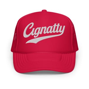 Könnte beinhalten: Rote Trucker-Cap mit weiß gesticktem Schriftzug "Cignatty" in einer Schreibschrift. Die Kappe hat eine Mesh-Rückseite und einen gebogenen Schirm. Die Kappe hat eine leuchtend rote Farbe.