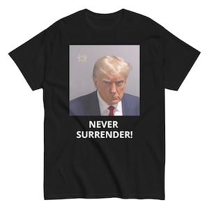 May include: Black t-shirt with a white image of a man in a suit and tie. The text "NEVER SURRENDER!" is printed below the image.