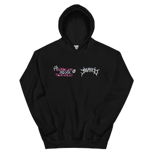 May include: Black hooded sweatshirt with the text "SIGUE NO ME SIGUE" in pink and white, and the word "HAYCH" in white. The sweatshirt has a front pocket and a drawstring hood.