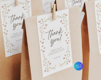 May include: Thank you gift bags with a floral and butterfly design. The bags are brown and have a white tag attached with the text "Thank you!" and "Amelia's Graduation 25.05.XX".