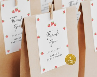May include: Thank you gift bags with white tags featuring a strawberry pattern and the text "Thank You" and "Haley's Baby Shower". The tags are attached to brown paper bags with a clothespin.