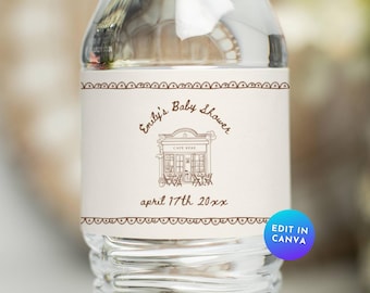 Könnte beinhalten: Eine transparente Wasserflasche mit einem individuellen Etikett für eine Babyparty. Das Etikett ist beige mit braunem Text und einem dekorativen Rand. Der Text lautet "Emily's Baby Shower" und "april 17th 20xx". Eine Grafik eines Cafés ist ebenfalls abgebildet.