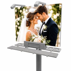 May include: A rectangular billboard display stand in gray plastic featuring a printed photograph of a bride and groom in wedding attire. The stand includes a central pole, a horizontal platform with grid details, and two top-mounted light fixtures.