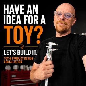 May include: A digital caliper held in front of a black background with white and orange text that reads: HAVE AN IDEA FOR A TOY? LET'S BUILD IT. TOY & PRODUCT DESIGN CONSULTATION. The caliper features a clear LCD screen displaying numerical measurements.