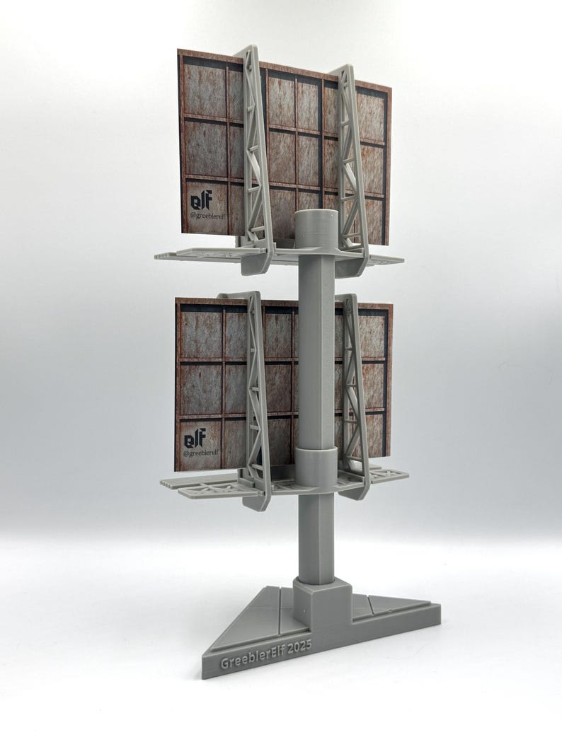 May include: A gray 3D-printed model of a double-stacked billboard structure with a central support pole and triangular base. The billboards feature a brown, grid-patterned surface with the text "elf @greeblerelf" and the base reads "GreeblerElf 2025".
