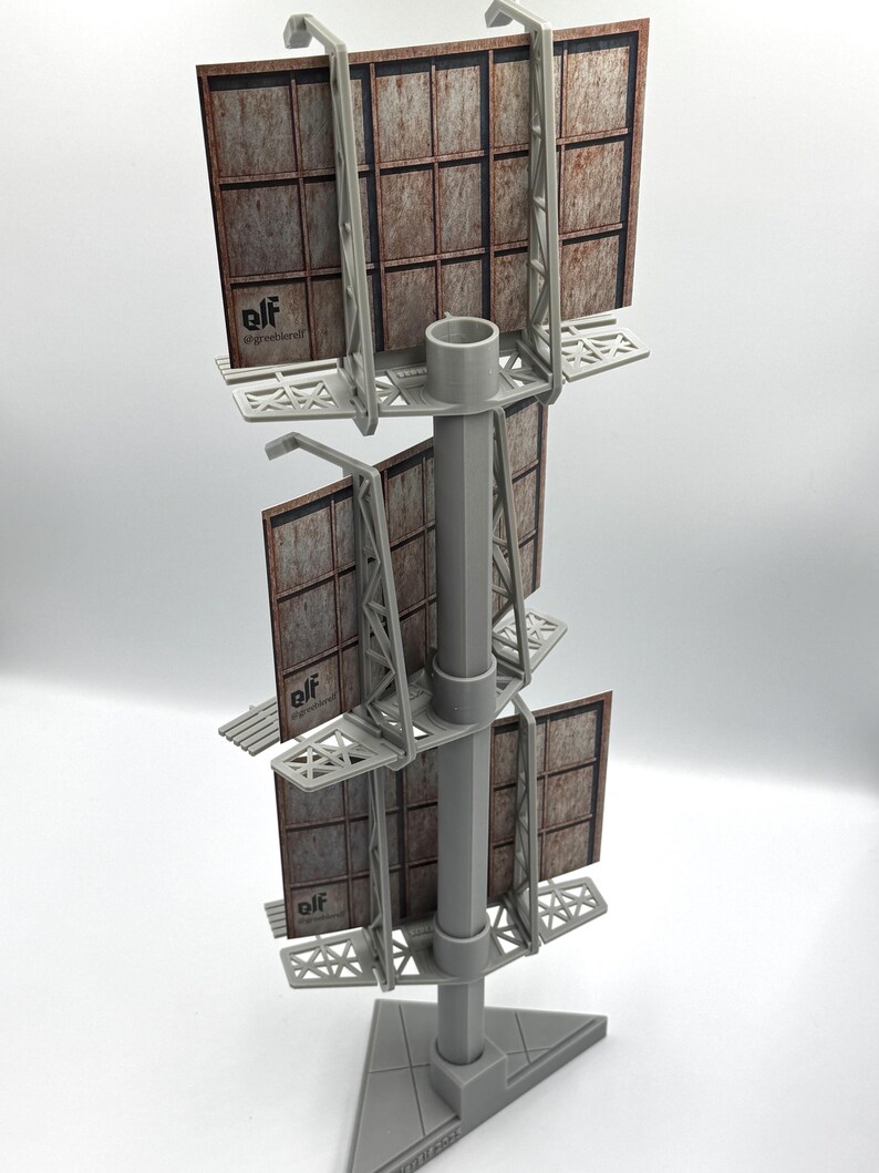 May include: A three-tiered gray plastic model billboard structure featuring a central vertical pole and a triangular base. Each level holds a rectangular sign with a weathered, rusted metal texture and the printed text elf @greethkrell.