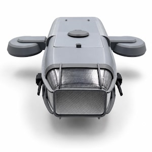 May include: A gray, elongated, rectangular device with a metallic, textured front panel encased in a protective frame. It features two side-mounted, rounded, gray protrusions and a smooth, flat top surface with a circular button and a small square tab.