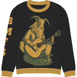 Könnte beinhalten: Schwarzer Langarm-Pullover mit goldfarbenem Besatz. Der Pullover zeigt ein Motiv einer Ziege, die Gitarre spielt. Der Text "B.M.E.S." ist auf dem linken Ärmel aufgedruckt.