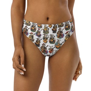 May include: High-waisted white bikini bottoms with a repeating pattern of goats playing guitars. The goats are depicted in various poses and outfits, with guitars in hand. The bikini bottoms have a high-cut leg and a full coverage back.
