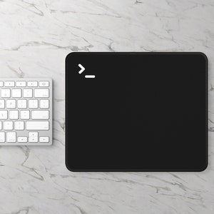 May include: A black mouse mat with a white "_" command line prompt symbol in the top left corner. The mouse mat is on a white marble surface.