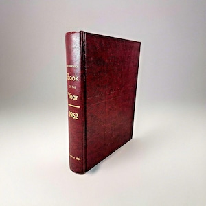 May include: A burgundy leather-bound book titled "Book of the Year 1962" with the word "Britannica" printed on the spine.