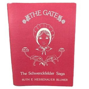 May include: A red book cover with a white illustration of a girl wearing a bonnet and holding a flower. The title "The Gate" is written in white above the illustration. The text "The Schwenckfelder Saga" and "RUTH E HESSENAUER BLUMER" are written in white below the illustration.