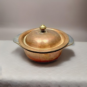 May include: A vintage copper serving dish with a lid and two handles. The dish has a brass knob on the lid.