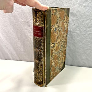 May include: A vintage hardcover book with a green and gold marbled cover. The spine reads "PRESCOTT'S HISTORICAL AND MISCELLANEOUS."