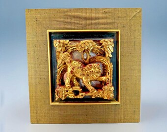May include: A framed, gold-colored relief carving depicting a horse with intricate details. The carving is set against a dark background within a gold frame, encased in a larger, textured, gold-toned frame. The artwork is square in shape.