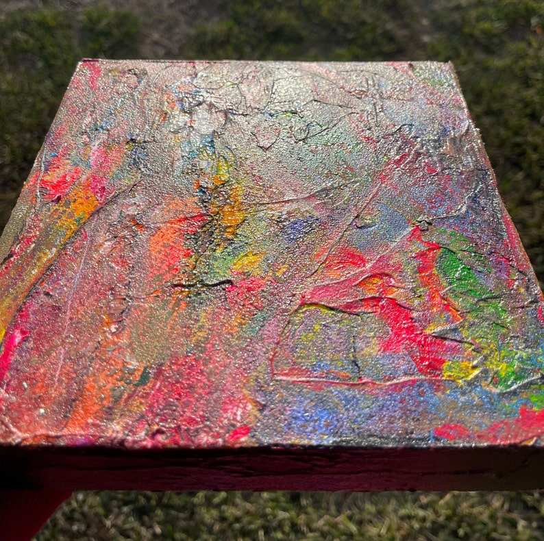 Pu&ograve; includere: Dipinto astratto su tela con una superficie strutturata. Il dipinto presenta una miscela di colori, tra cui rosso, giallo, blu, verde e argento. I colori sono mescolati insieme in un motivo vorticoso, creando una composizione dinamica ed energica.