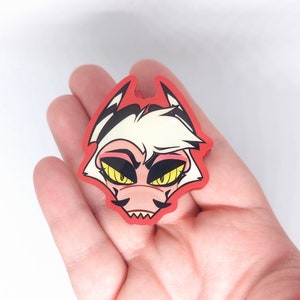 May include: A red and white cartoon character sticker with yellow eyes and a pink nose. The character has a mischievous expression and is wearing a red collar.