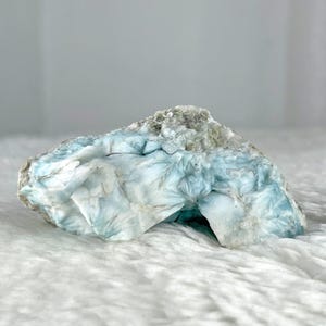 May include: A blue and white crystal with a unique, swirling pattern. The crystal has a rough, natural texture and is a beautiful example of a natural gemstone.