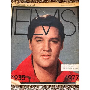 Pode incluir: Uma cópia vintage do jornal The Courier-Journal de 22 de agosto de 1977, com um retrato de Elvis Presley na capa. A manchete diz "ELVIS" em letras grandes. A imagem inclui os anos de 1935 e 1977.