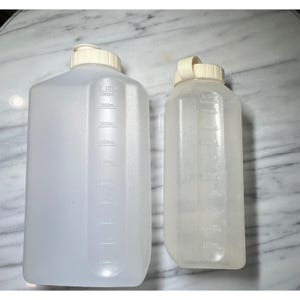 Peut inclure: Deux bouteilles en plastique transparent avec des bouchons à vis blancs. La plus grande bouteille a une capacité de 2 litres, avec des graduations en millilitres. La plus petite bouteille a également des graduations en millilitres. Les deux bouteilles sont vides et semblent propres.