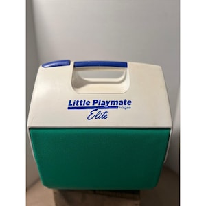 May include: A white and green Little Playmate Elite cooler by Igloo. The cooler has a blue handle and the words "Little Playmate Elite" are printed on the front in blue. The cooler is designed to keep items cold.