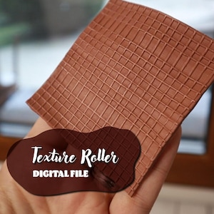 Puede incluir: Un rodillo texturizado marrón para crear patrones en arcilla o fondant. El rodillo tiene un patrón de cuadrícula y está hecho de un material flexible. El texto "Texture Roller DIGITAL FILE" es visible en la imagen.