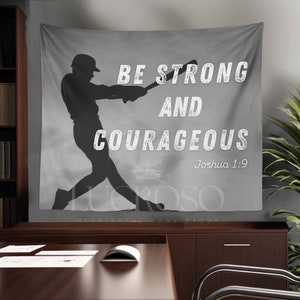 May include: A gray baseball-themed wall tapestry featuring a silhouette of a batter swinging a bat. The text "BE STRONG AND COURAGEOUS" is displayed in white, along with the Bible verse Joshua 1:9. The tapestry is a piece of home decor.