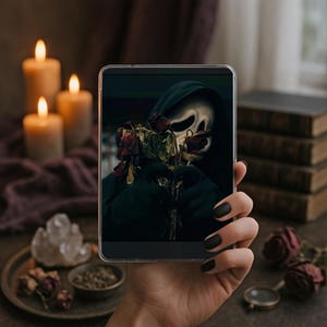 May include: A tablet displays a spooky image of a figure in a black hooded robe and a white mask holding dried red roses. The background includes lit candles, crystals, and a stack of books, creating a gothic aesthetic.