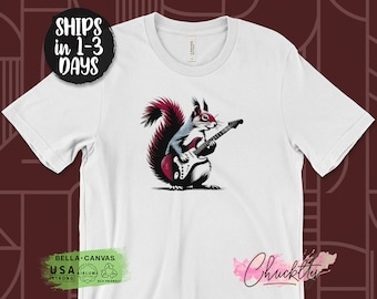 Könnte beinhalten: Weißes T-Shirt mit einem Aufdruck eines Eichhörnchens, das eine E-Gitarre spielt. Das Eichhörnchen ist rot und schwarz, und die Gitarre ist rot, schwarz und weiß.
