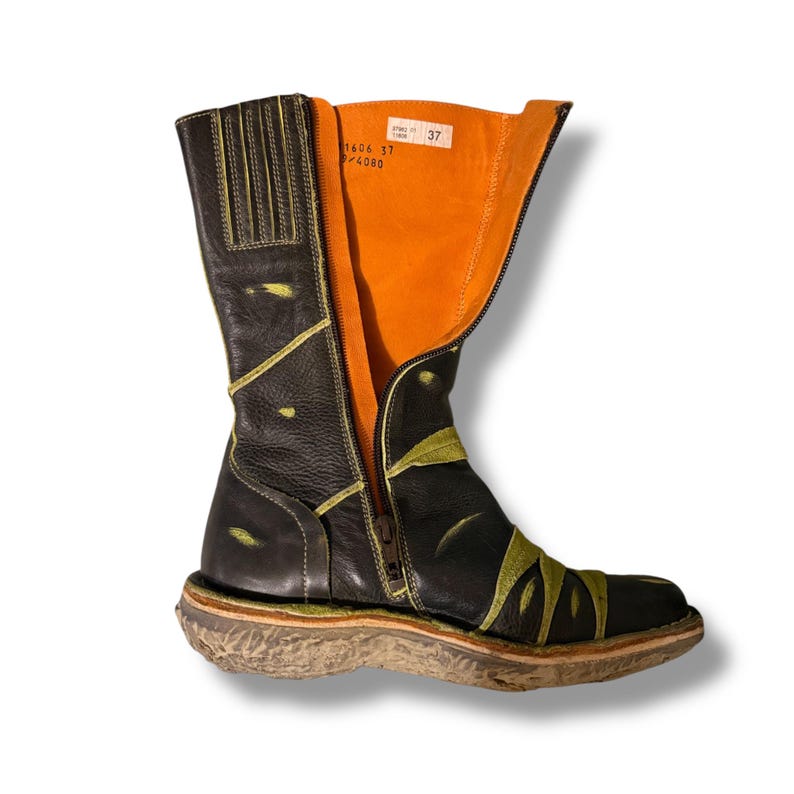 May include: Black leather boot with a side zipper, featuring green leaf-like accents and a tan sole. The interior is bright orange. The boot has the numbers "1606 37" and "/4080" printed on a tag.