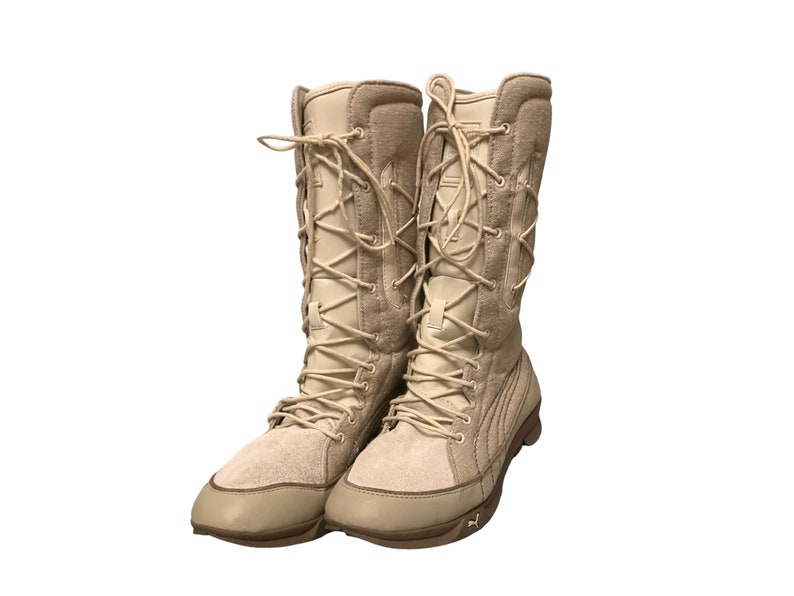 May include: A pair of tan suede high-top boots with lace-up closures. The boots have a thick rubber sole and a padded ankle collar.