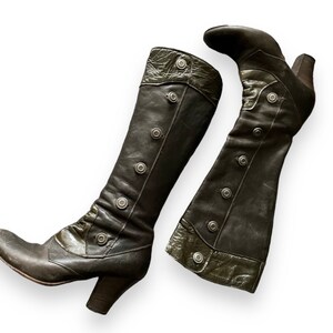 May include: A pair of brown leather boots with a decorative button detail. The boots have a pointed toe and a block heel.