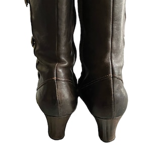 May include: A pair of brown leather heeled boots with a zipper on the inside of each boot.