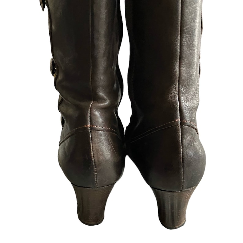 May include: A pair of brown leather heeled boots with a zipper on the inside of each boot.