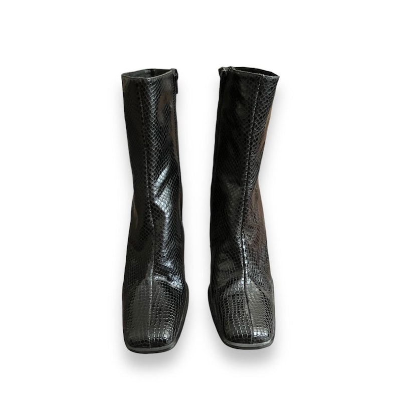 May include: A pair of black ankle boots with a snakeskin pattern. The boots have a square toe and a low heel.
