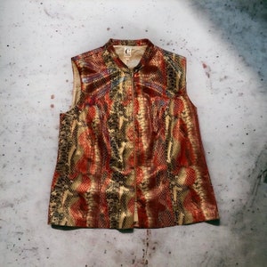 May include: A sleeveless vest with a zip fastening. The vest is made from a snakeskin-patterned fabric in shades of gold, red, and black.
