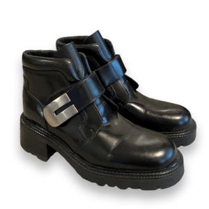 May include: Black leather ankle boots with silver buckles and chunky platform soles.