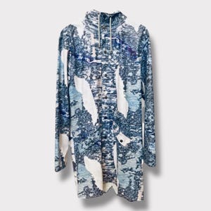May include: A long-sleeved jacket with a high neck and a zipper closure. The jacket is made of a white fabric with a blue and white abstract print.