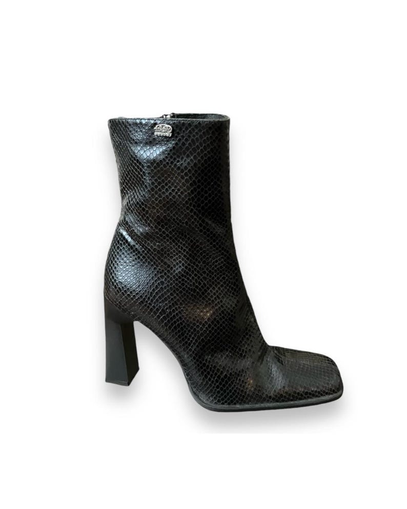 May include: Black ankle boots with a snakeskin pattern and a square toe. The boots have a chunky block heel.