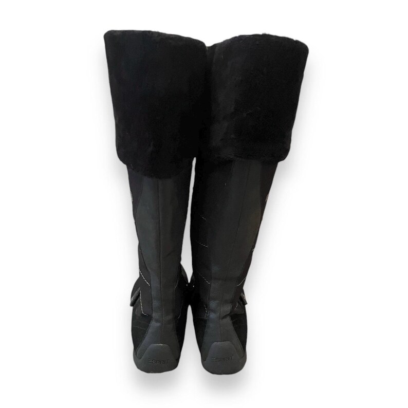 May include: A pair of black knee-high boots with a faux fur cuff. The boots have a zipper on the inside of the ankle and a buckle strap across the top of the foot.